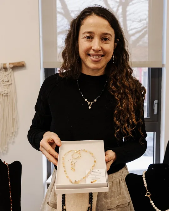 The maker of 4 the Love of Pretty Things at her market table, holding a box of handmade necklaces